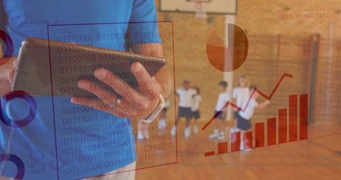 Coach analyzing tablet data while tracking student athletes performance in school gym
