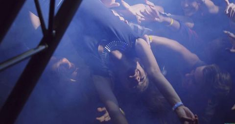 Dynamic crowd-surfing with energetic blue haze at concert