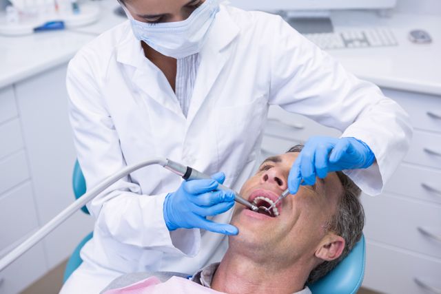 Dentist examining patient in a medical clinic, focusing on dental care and oral health. Suitable for use in healthcare, dental care, and medical professional contexts. Ideal for illustrating dental services, patient care, and professional healthcare environments.