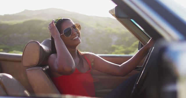 Portrait of african american woman sitting in the convertible car on road. road trip travel and adventure concept