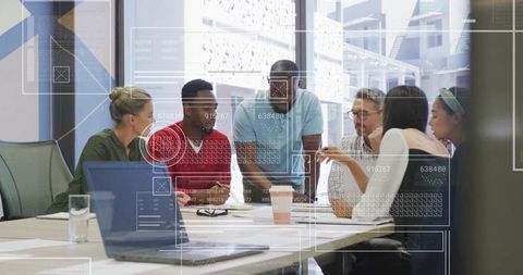 Diverse team collaborating over laptop during modern office brainstorming session