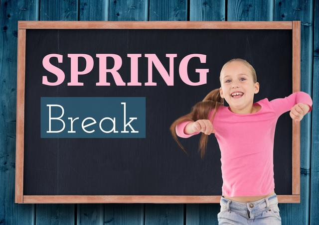 Young girl in a classroom, enthusiastically celebrating the start of spring break. She is wearing a pink shirt and standing in front of a blackboard with the text 'Spring Break.' This image is ideal for educational content, school promotions, seasonal campaigns, holiday advertisements, or any materials highlighting childhood joy and education.