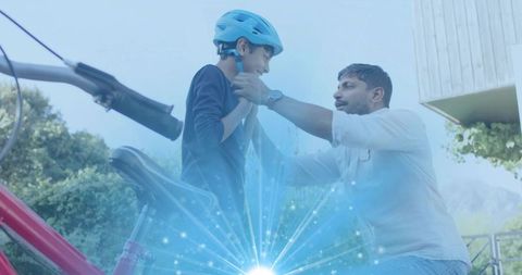Father fastening helmet on son before neighborhood bike ride, outdoor safety moment