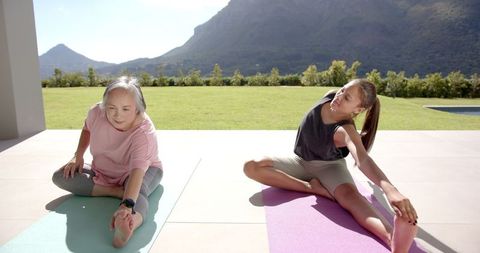 Grandmother and Granddaughter Doing Stretching Exercises Outdoors