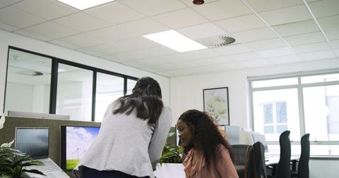 Diverse coworkers collaborating at modern office workstation