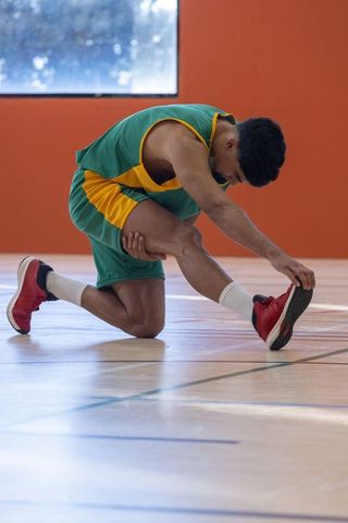 Male Athlete Stretching on Gym Court in Sports Gear