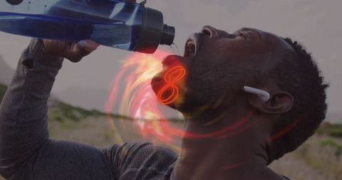 Athlete drinking from blue bottle with glowing red energy aura, earbuds, dune closeup