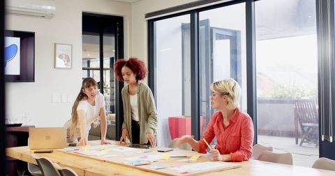 Diverse Team Collaborating at Office with Laptop and Sketches