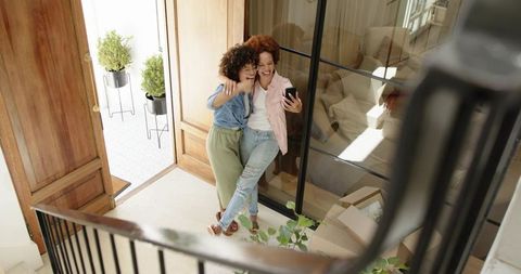 African American friends moving into new home taking selfie in sunlit entryway