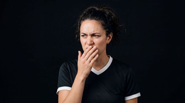 Woman covering mouth and squinting in contemplative mood wearing black sports tee