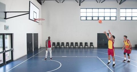 Basketball training with coach and players shooting on indoor court
