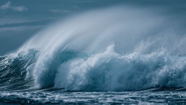 Powerful ocean wave crashing and curling with sea spray, foamy breaker and wind-swept mist