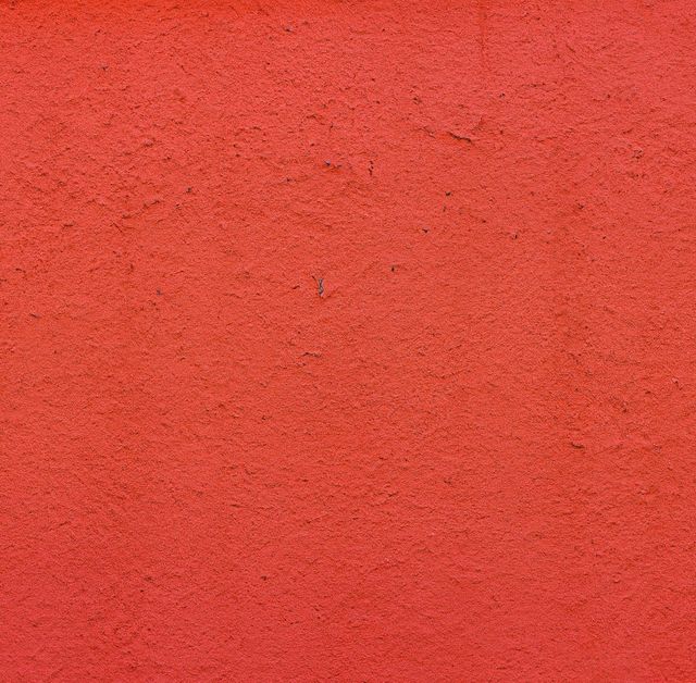 Bright red textured wall offers bold, vibrant background ideal for graphic design, advertising, marketing materials. Use for digital content, wallpaper, presentations, artistic projects.