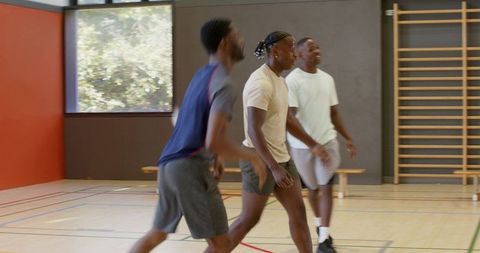 African american players sprinting after rebound during indoor basketball practice