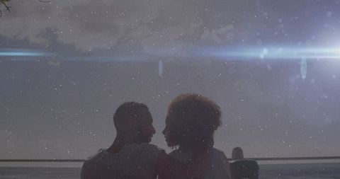 Couple Leaning Together Watching Starry Seascape on Seawall at Night with Lens Flare