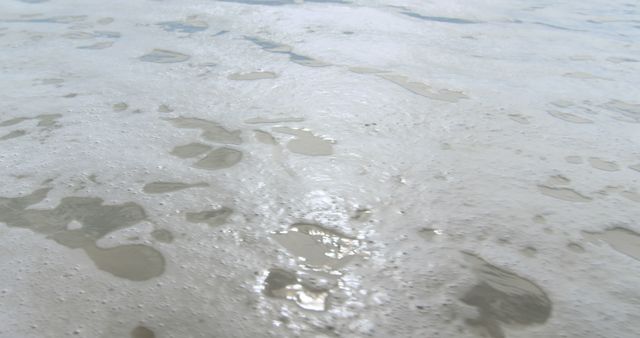 Foamy sea water recedes on the sandy beach, creating patterns - Download Free Stock Photos Pikwizard.com