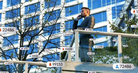 Businessman standing on terrace making phone call while receiving social media alerts