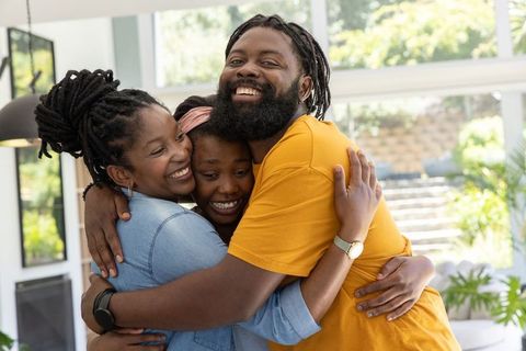 African family sharing warm group hug in sunlit modern living room, smiling and joyful