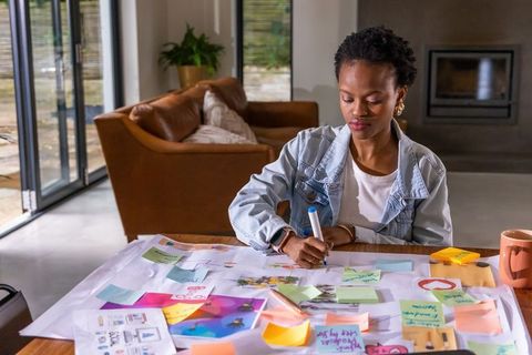 African american woman planning design project in home workspace with sticky notes