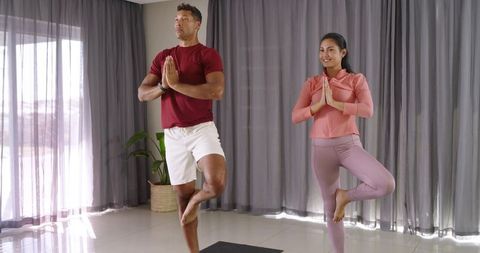 Couple Practicing Tree Pose Together in Sunlit Home Studio for Wellness and Balance