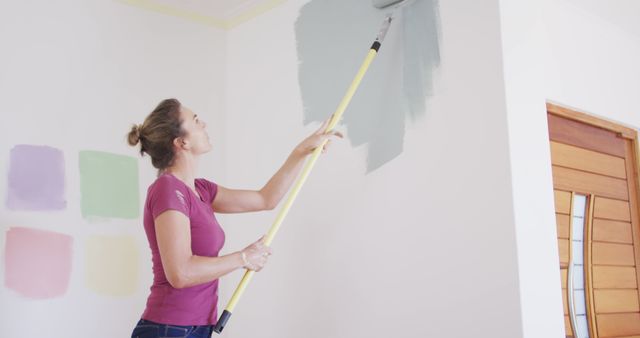 Focused caucasian woman painting wall with gray paint. Lifestyle, domestic life, house interior and work, unaltered.