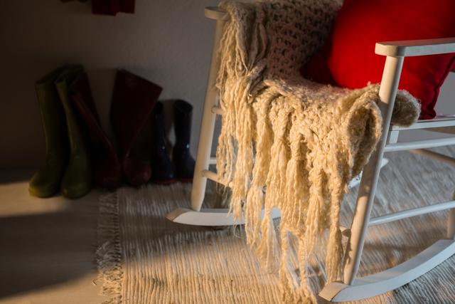 Wooden chair with red pillow and woolen blanket at home