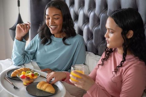 Friends Sharing Breakfast in Bed with Laughter and Joy