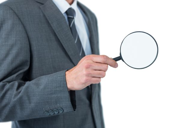 Businessman in a suit holding a magnifying glass, symbolizing inspection, investigation, and attention to detail. Useful for business, corporate, and professional themes, as well as concepts related to analysis, scrutiny, and thorough examination.