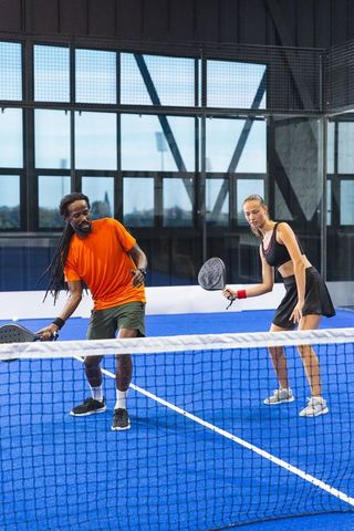 Multiracial athletes engaged in energetic padel match indoors