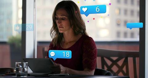 Woman Reading Tablet Receiving Social Media Notifications in Urban Cafe