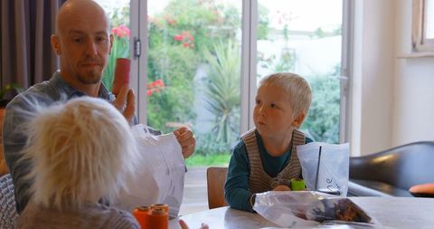 Father Engaging with Children over Craft Supplies at Home