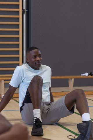 African american man sitting on gym floor cooling down after workout in indoor gym