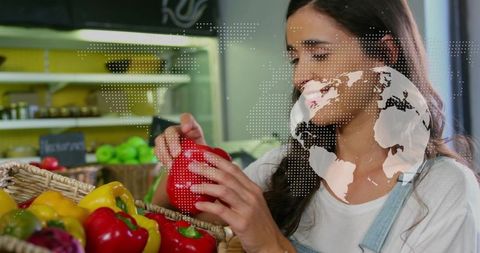 Young woman selecting red bell pepper in bright market with woven basket and fresh produce