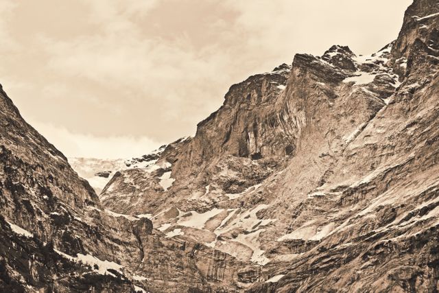 Rugged mountain range with snow-capped peaks in sepia tone, evoking a vintage feel. Ideal for use in nature-themed campaigns, travel brochures, adventure-related content, or vintage-inspired designs.