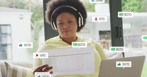 Woman with Headphones Reviewing Social Engagement on Laptop