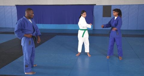 Diverse athletes practicing judo stances on tatami mat