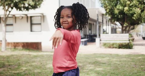 Confident young girl in schoolyard on sunny day