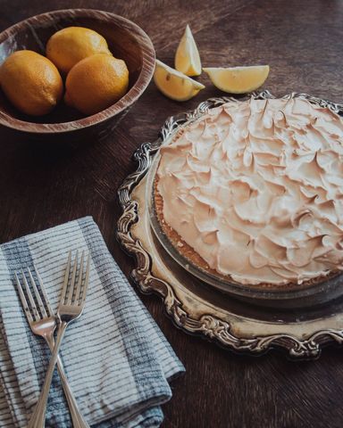 Lemon Pie on Elegant Tray Next to Whole and Sliced Lemons