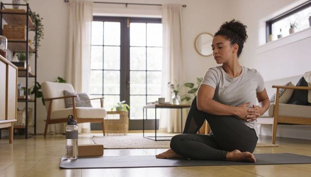 Woman stretching on yoga mat in bright living room practicing mindful home workout
