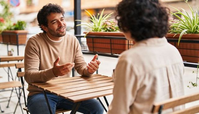 Man enjoying casual conversation at sidewalk cafe terrace, urban daytime meeting