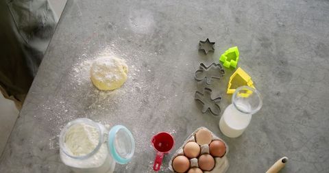 African American man rolling cookie dough on gray countertop with cutters and baking tools