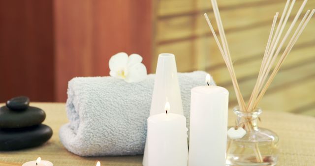 A tranquil spa setting features lit candles, fluffy towels, and aromatic diffusers, with copy space. Elements in the image evoke a sense of relaxation and promote wellness and self-care.