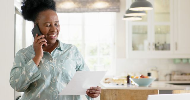 Smiling Woman in Kitchen Talking on Phone and Reviewing Documents - Download Free Stock Images Pikwizard.com