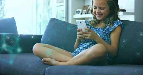 Happy Girl Enjoying Smartphone on Comfortable Sofa at Home
