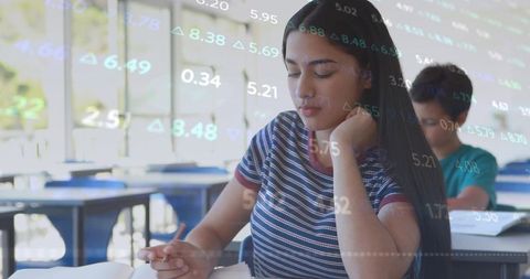 Teen Girl Studying with Data Overlay in Bright Classroom, Reading Workbook and Focusing