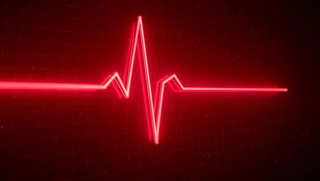 Glowing red ecg waveform neon heartbeat trace on dark grid medical monitor background