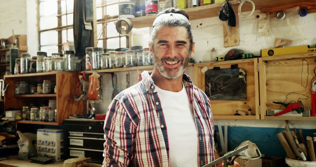 Middle-Aged Man Smiling in Workshop with Tools and Supplies - Download Free Stock Images Pikwizard.com