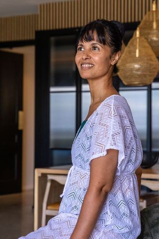 Smiling african american woman wearing white lace coverup gazing left in modern dining