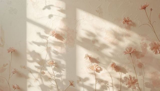 Sunlight casting leaf shadows on textured plaster with peach floral wallpaper