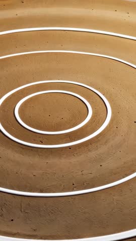 Vertical video capturing white concentric rings on textured sand for abstract geometric minimalism